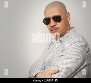 Mid forties bold guy with mustaches  wearing a shirt and aviator type sunglasses posing for studio shot Stock Photo