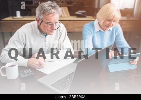 Old enterpreneur and his partner are working together on different gadgets. He is working with computer while is doing that on tablet. They look conce Stock Photo
