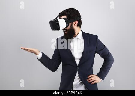 surprised businessman in VR glasses looking on empty hand, virtual reality concept, mock-up image Stock Photo