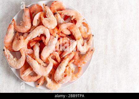 Frozen king prawns on a white plate on a light background Stock Photo