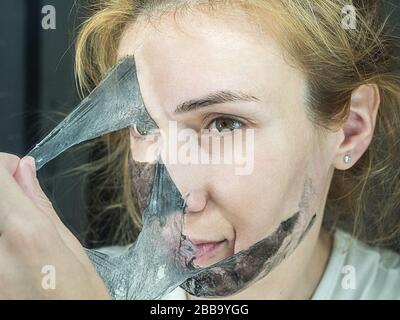 Girl rips off black thin transparent mask to clean face Stock Photo
