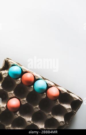 Painted easter eggs in carton box on white background. Trendy blue and red color. Top view. Paschal concept. Stock Photo