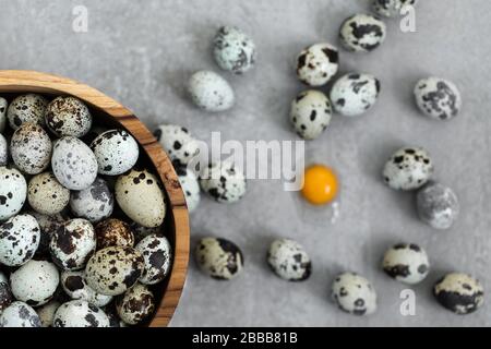 Wooden bowl with heap of small quail eggs on gray concrete background. Easter cooking concept. Stock Photo