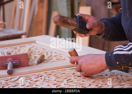 Close-up of the hands of a woodworker in the streets of Marrakesh, manually sculpting a piece of furniture. Stock Photo