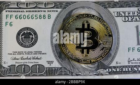 golden bitcoin coin on us dollars close up. Bitcoin mining: Miner figurine digging ground to uncover big shiny bitcoin. Stock Photo