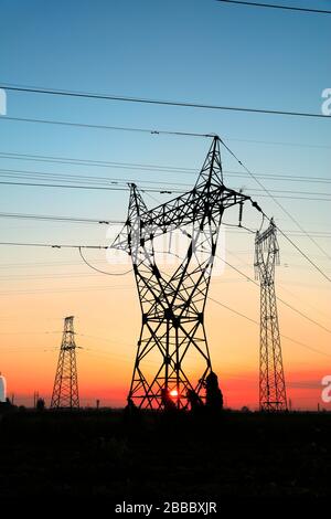 In the evening, high voltage towers silhouette and a beautiful sunset Stock Photo