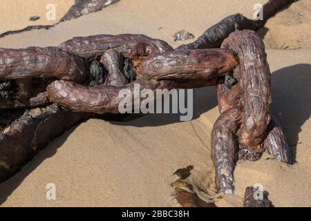 Old rusty chain in sand on beach Stock Photo