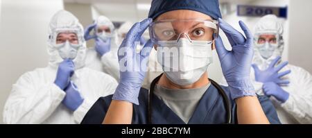 Team of Female and Male Doctors or Nurses Wearing Personal Protective Equiment In Hospital Hallway. Stock Photo