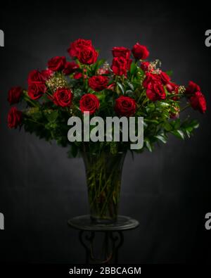 Three dozen, large stem, thorn-less roses in a large glass vase. Beautiful roses. Stock Photo