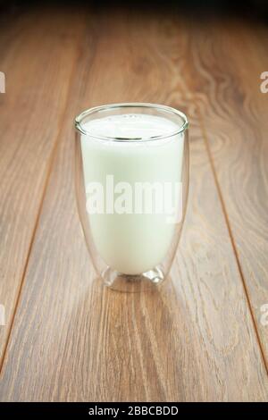 Full glass of milk for a breakfast on a wooden table splashes of milk. Stock Photo