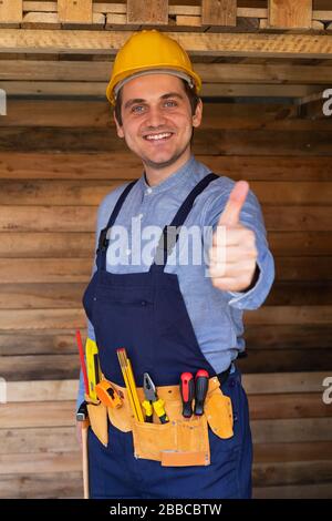 Portrait of a confident young workman wearing yellow helmet, blue uniform - DIY renovation concept Stock Photo