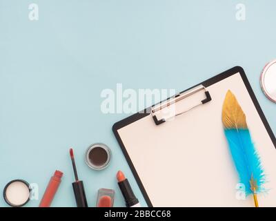 Beauty composition with clipboard with white blank paper on it, cosmetics, makeup products and accessories isolated on pastel blue background. Top vie Stock Photo