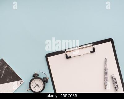 School stationery supplies, back to school concept. Black clipboard with white blank empty paper with pen on it, black alarm clock, black and white no Stock Photo
