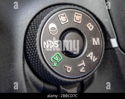 Round button for selection scene and mode on digital mirror camera, close up. Dial of programs on the modern camera, macro view. Stock Photo