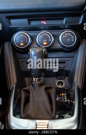 The gear shift of automatic transmission with air conditioning controls on the car dashboard. Focused at dashboard. Stock Photo