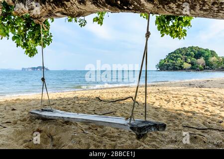 Rustic wooden swing hanging from tree with sea views on beach on Ko Yao Noi island, Phang-Nga Bay near Phuket, Thailand Stock Photo