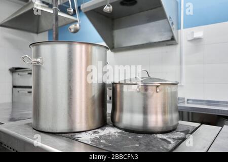 Closeup of large pots on the stove. Chef cooking at commercial kitchen - hot job. real dirty restaurant kitchen. Stock Photo