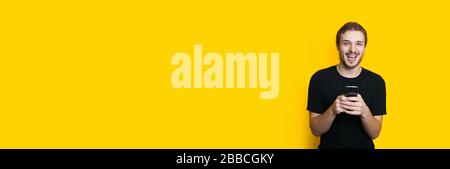 Happy caucasian man with beard and long hair is chatting with somebody on a yellow background with empty space Stock Photo