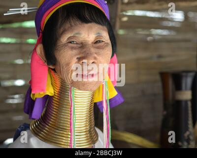 Old Thai/Burmese long-neck Kayan woman ('giraffe woman”) with polished tribal Padaung brass neck rings/coils poses for the camera. Stock Photo