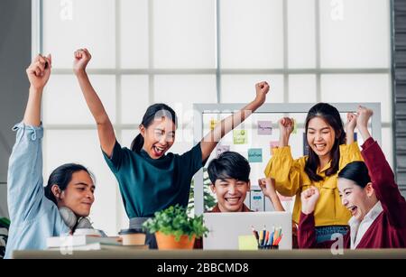 Asian ux developer and ui designer arms raise for successful design at modern office.Creative digital development agency Stock Photo