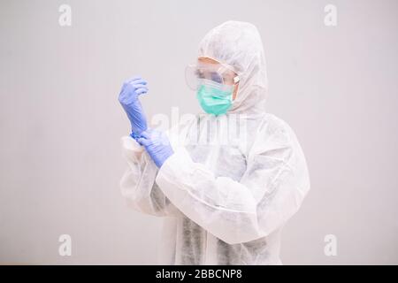 Young Nurse with disposable coverall wearing sterile gloves preparing take care of Pandemic 2019 Coronavirus 2019-nCoV. Stock Photo