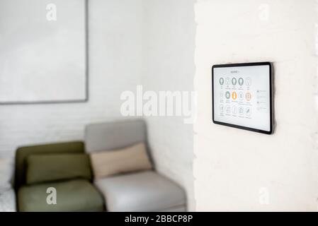 Touch screen panel with launched smart home software installed on the wall in the living room Stock Photo