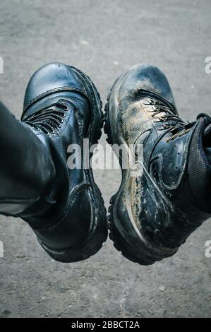 Two black boots. Muddy boots side by side from a man and a woman. Stock Photo