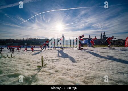 Men racing at the FIS cross-country skiing sprint World Cup on the banks of the river Elbe, the skyline of the baroque town in the distance Stock Photo