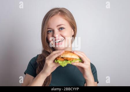 Smiling young Caucasian woman girl holding eating chicken burger Stock Photo