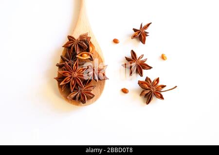 Food concept. Anise stars in a wooden spoon on a white background. Top view. Stock Photo