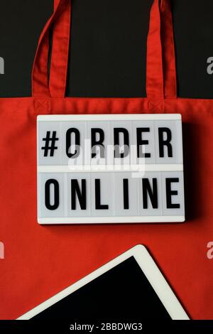 lightbox with words order online. Online shopping concept. Laptop with red cotton shopping bag on black background. Top view, flat lay, copy space. Ze Stock Photo