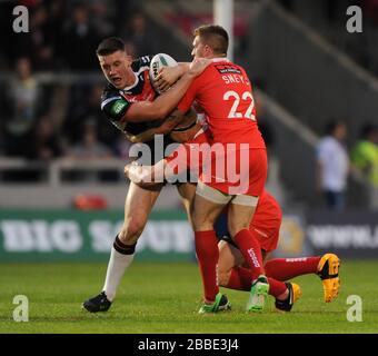 Salford City Reds' and St. Helens' Tom Makinson is tackled by Marc Sneyd (22) and Shannon McPherson (centre). Stock Photo