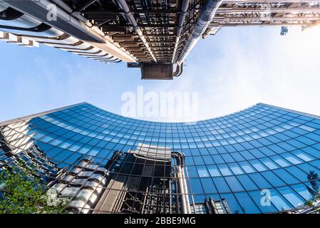 London, UK - May 14, 2019: Low angle view of office buildings in the City of London against blue sky. Reflections on glass