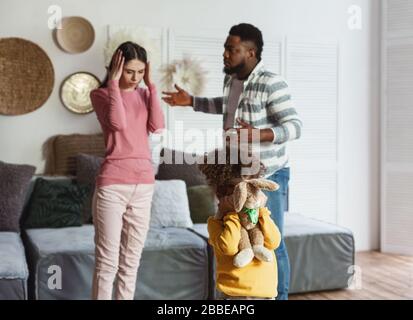 Divorce concept. International parents quarrel, daughter cries Stock Photo