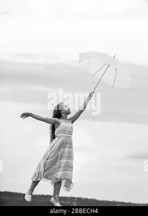 Girl with light umbrella. Fairy tale character. Happy childhood. Feeling light. Anti gravitation. Fly drop parachute. Dreaming about first flight. Kid pretending fly. I believe i can fly. Touch sky. Stock Photo