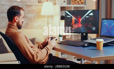 Game developer testing new joystick for shooter game from home office at night. Stock Photo