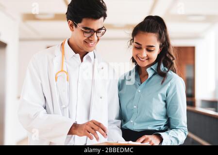Two young doctors are discussing something in the hallway in a hospital Stock Photo