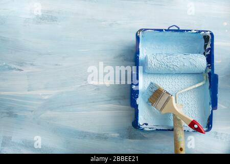 Tray, roller and brush for painting walls on blue background Stock Photo