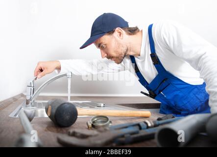 An installer works on a sink in an apartment Stock Photo