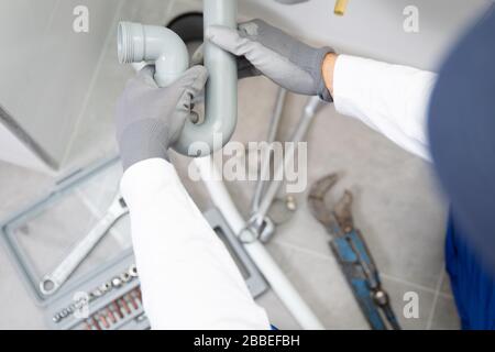 An installer works on a sink in an apartment Stock Photo