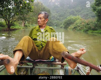 local man rowing tourists on the River in Tam Coc, Ninh Binh, Vietnam Stock Photo