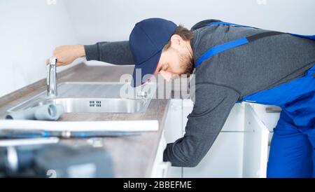 An installer works on a sink in an apartment Stock Photo