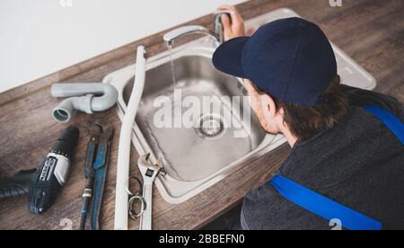 An installer works on a sink in an apartment Stock Photo