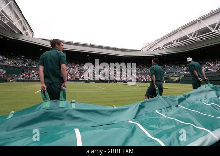 Groundstaff race to put the covers on centre court as rain stops play during the match between Poland's Agnieszka Radwanska and France's Mathilde Johansson during day four of the Wimbledon Championships at The All England Lawn Tennis and Croquet Club, Wimbledon. Stock Photo