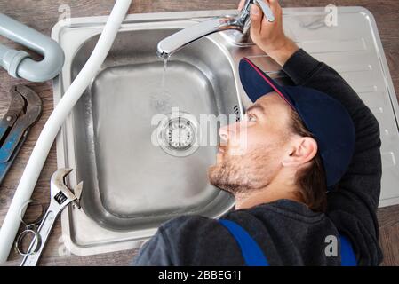 An installer works on a sink in an apartment Stock Photo