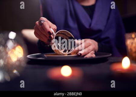 Close-up of fortuneteller's hands divining on coffee grounds at table with predictive ball in room Stock Photo