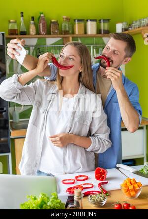 Young loving family has fun with organic pepper while cooking fresh salad Stock Photo