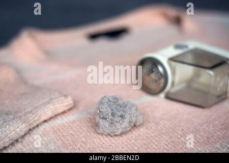 Pilled sweater. Handheld electric fabric shaver fuzz remover device machine for removing fuzz, lint and pills on clothes. Stock Photo