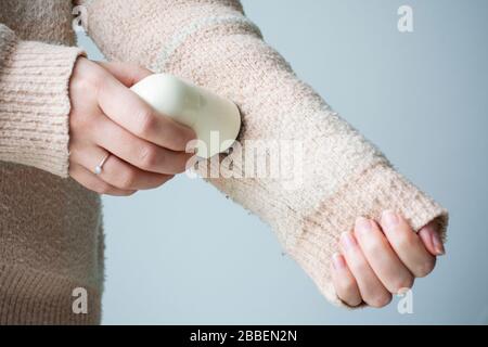 Pilled sweater. Woman wearing an old sweater with lint (pilling). Woman use handheld electric fabric shaver fuzz remover device machine Stock Photo
