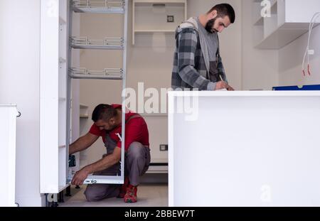 two professional workers installing a new stylish modern kitchen furniture Stock Photo